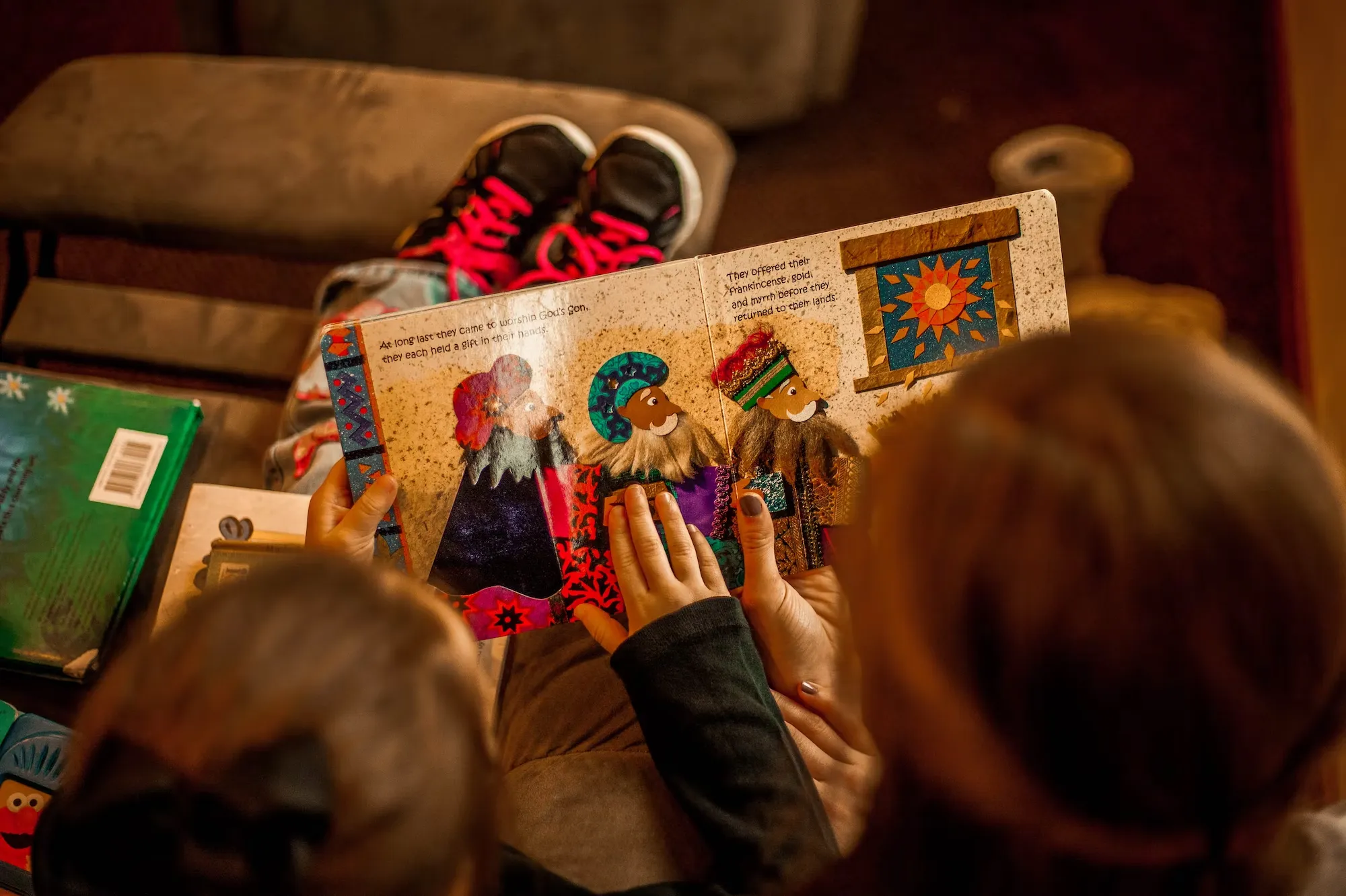 

The image shows a young girl sitting in a library, surrounded by books. She is looking intently at one of the books, with a smile on her face. The image conveys the joy of discovering a book that is interesting and enjoyable