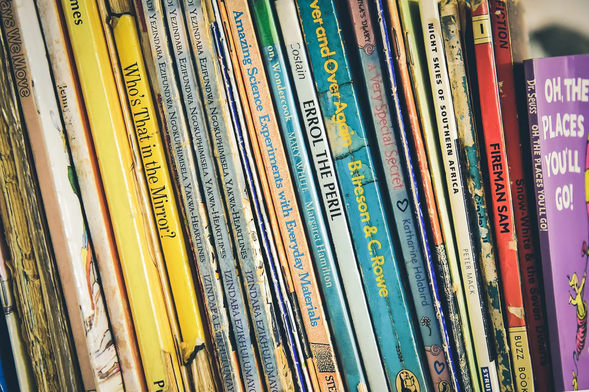 

An image of a smiling child sitting in a comfortable chair, surrounded by a variety of books, with a look of contentment on their face. The image conveys the idea that books can be used to help children build self-confidence and