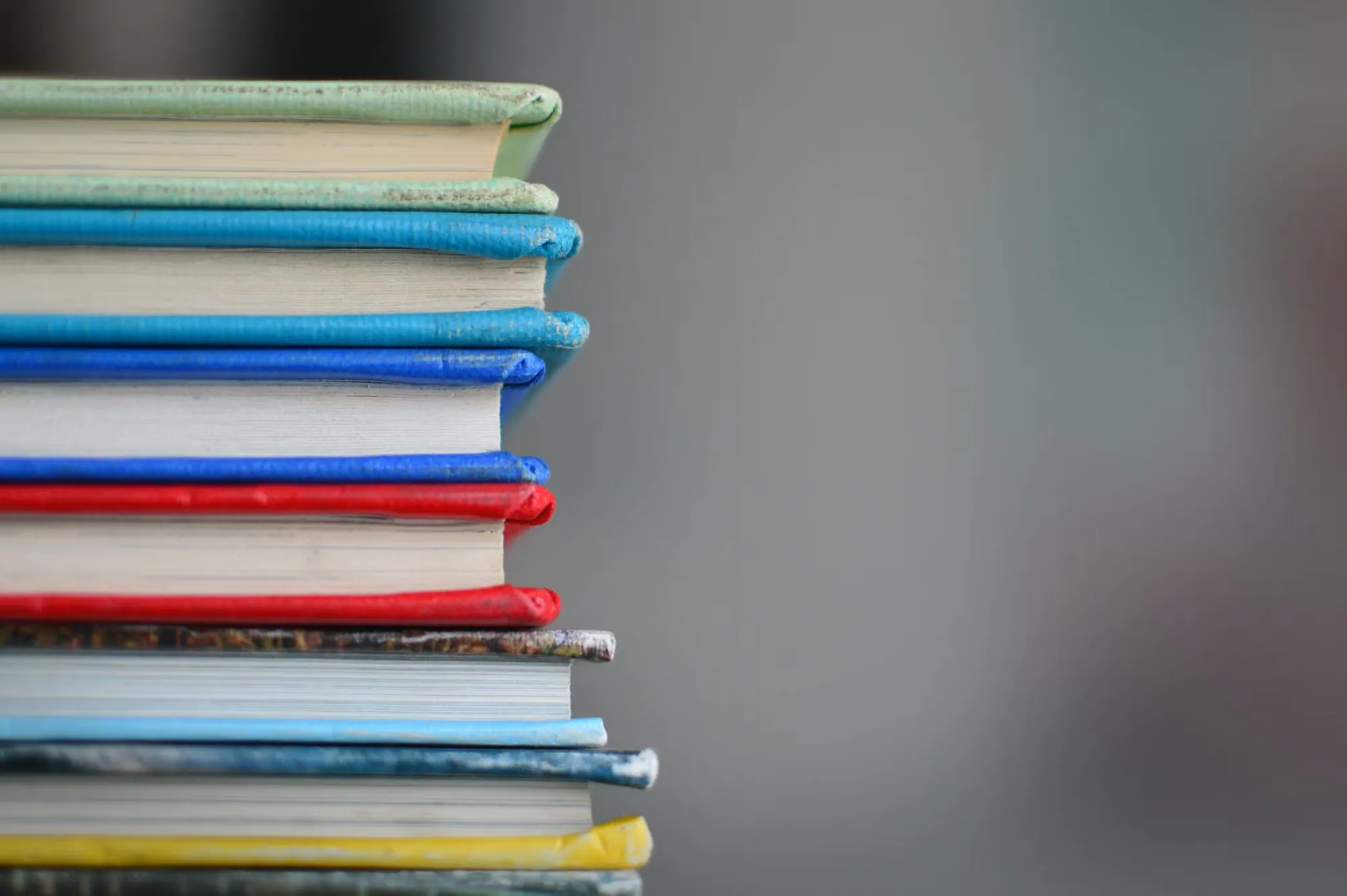 

The image shows a young child sitting in a chair with a book in their lap. The child is smiling and looking intently at the book, demonstrating the joy and engagement that books can bring to children. This image illustrates the positive impact that